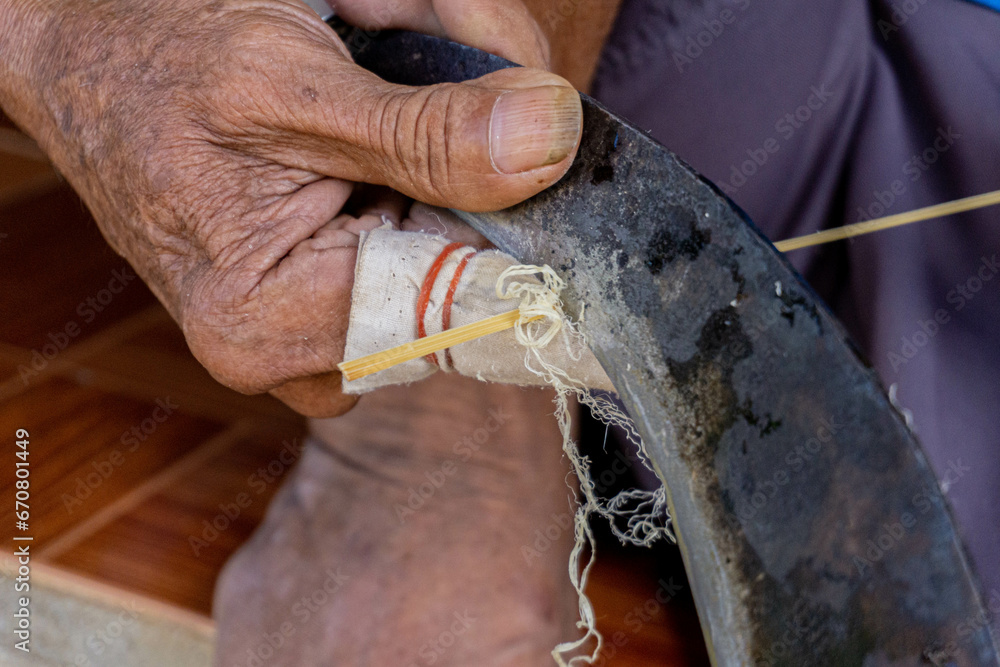 Obraz premium A carpenter sharpens bamboo to use in crafts.