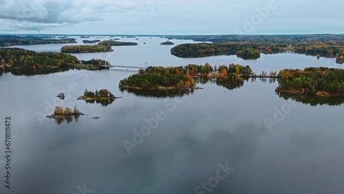 Approaching a bridge crossing a huge lake and it's archipelago islands surrounded by an autumn forest with red, green yellow and brown trees. photo