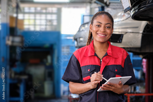 Happy Black female supervisor mechanic, cheerful smile, inspects repair work checklists with tablet at garage, service car maintenance, and fixing specialist occupations in auto transport industry.