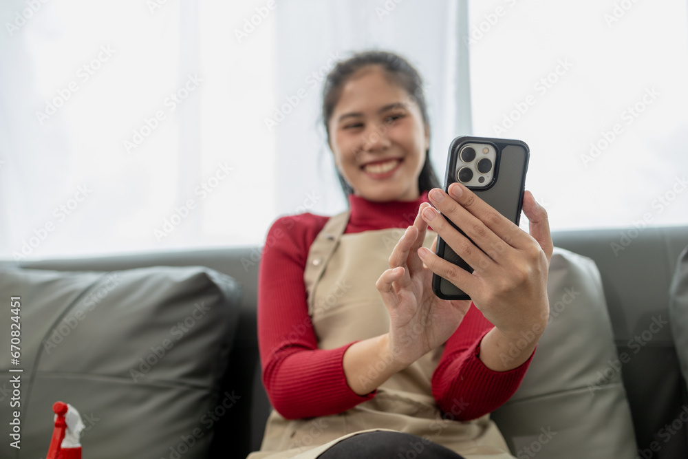The housekeeper is relaxing after cleaning the house, Playing on the phone on the sofa, Watch videos on your smartphone after cleaning the house, relaxing idea. The housekeeper is relaxing after cleaning the house, Playing on the phone on the sofa, Watch videos on your smartphone after cleaning the house, relaxing idea.