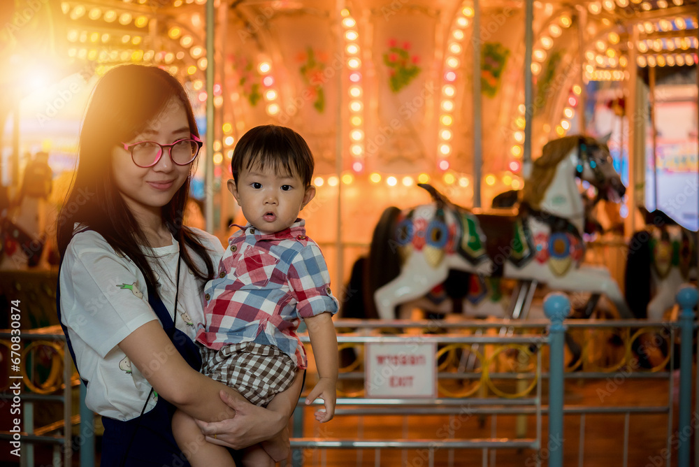 Portrait of happy mother and baby boy in amusement park night Portrait of happy mother and baby boy in amusement park night