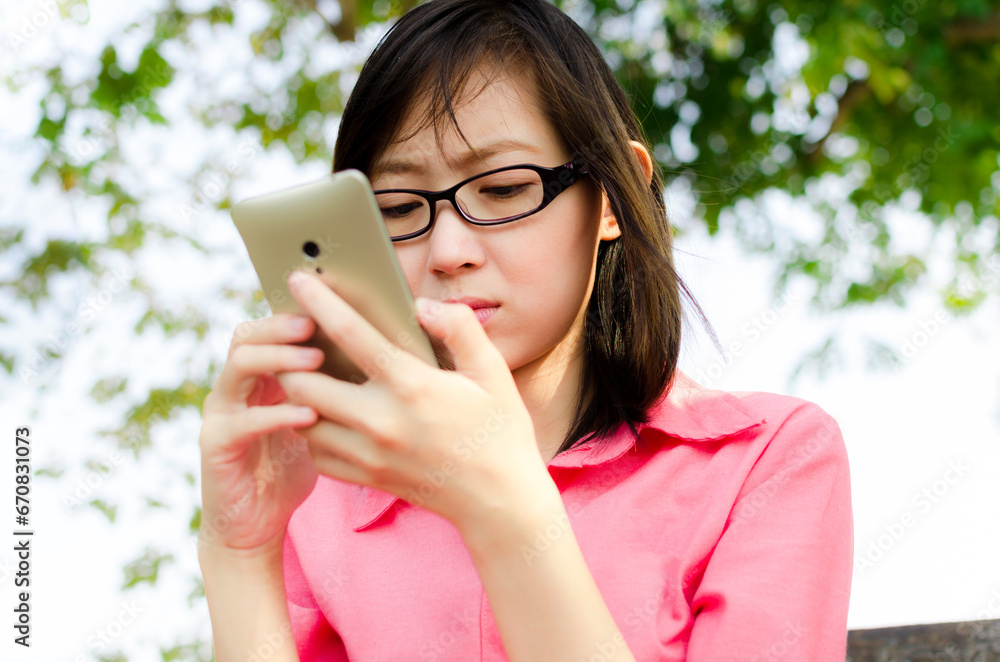 Upset confused asian young woman suing mobile phone reading text message Upset confused asian young woman suing mobile phone reading text message