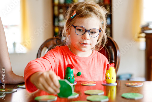 Family playing board game at home. Kids play strategic game. Little sister girl moving part of table game. Fun indoor activity. Siblings bond. Educational toys.