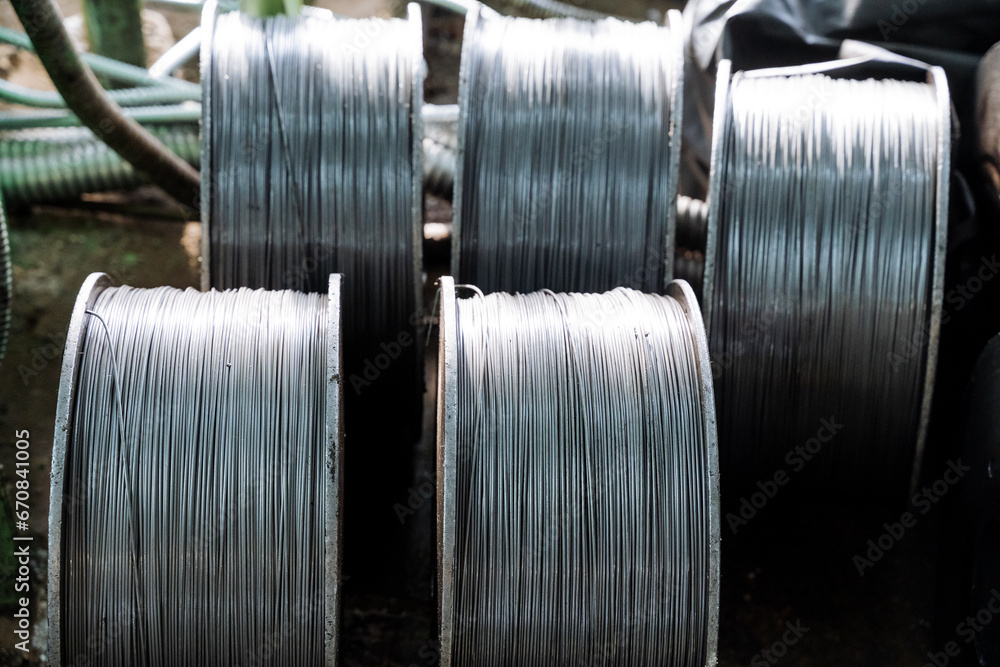 Wire production in the factory, metal wire in the coil stands on the floor in the workshop, metallurgical production of iron thread. Wire production in the factory, metal wire in the coil stands on the floor in the workshop, metallurgical production of iron thread.