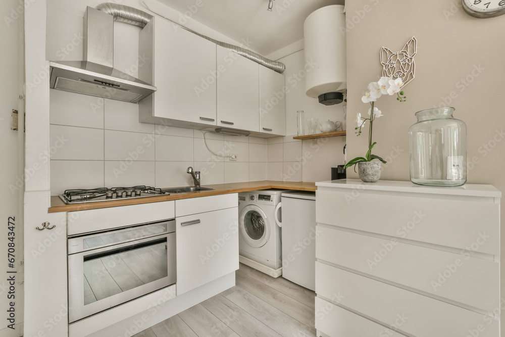 a small kitchen with white cupboards and wooden counter tops on the wall above it is a glass vase filled with flowers a small kitchen with white cupboards and wooden counter tops on the wall above it is a glass vase filled with flowers