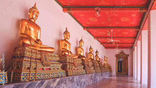 Row of golden buddha statues on marble base with corridor inside of Wat Pho or Wat Phra Chetuphon Wimon Mangkhalaram, perspective side view © Prapat