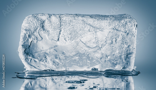 A big rectangular textured transparent piece of ice on a blue background. photo