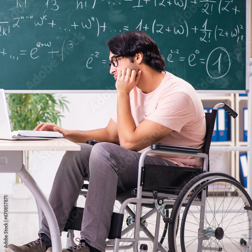 Young handsome man in wheelchair in front of chalkboard photo