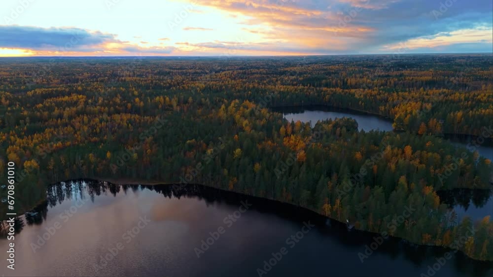 Sun has just set over Fiskträsk lake in Sipoonkorpi National Park, Finland. The dusk sky is reflected off the surface. Autumn is turning the trees yellow, red, green and brown. Camera moving left. Sun has just set over Fiskträsk lake in Sipoonkorpi National Park, Finland. The dusk sky is reflected off the surface. Autumn is turning the trees yellow, red, green and brown. Camera moving left.