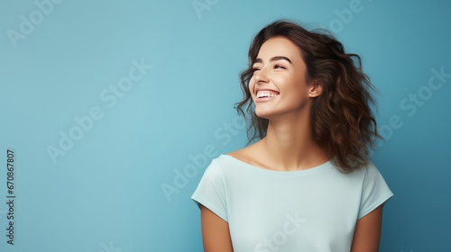 American woman standing in front of a blue background, showing a cheerful and caring smile. Romantic concept.