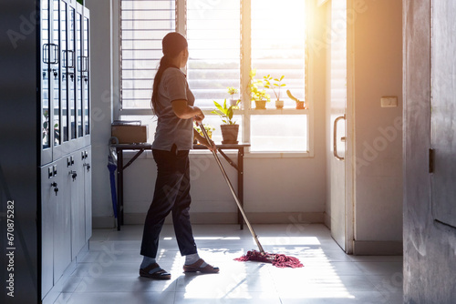 Janitor woman mopping floor in hallway office building or walkway after school or classroom with blank copy space. Housekeeper working job with sun light background.