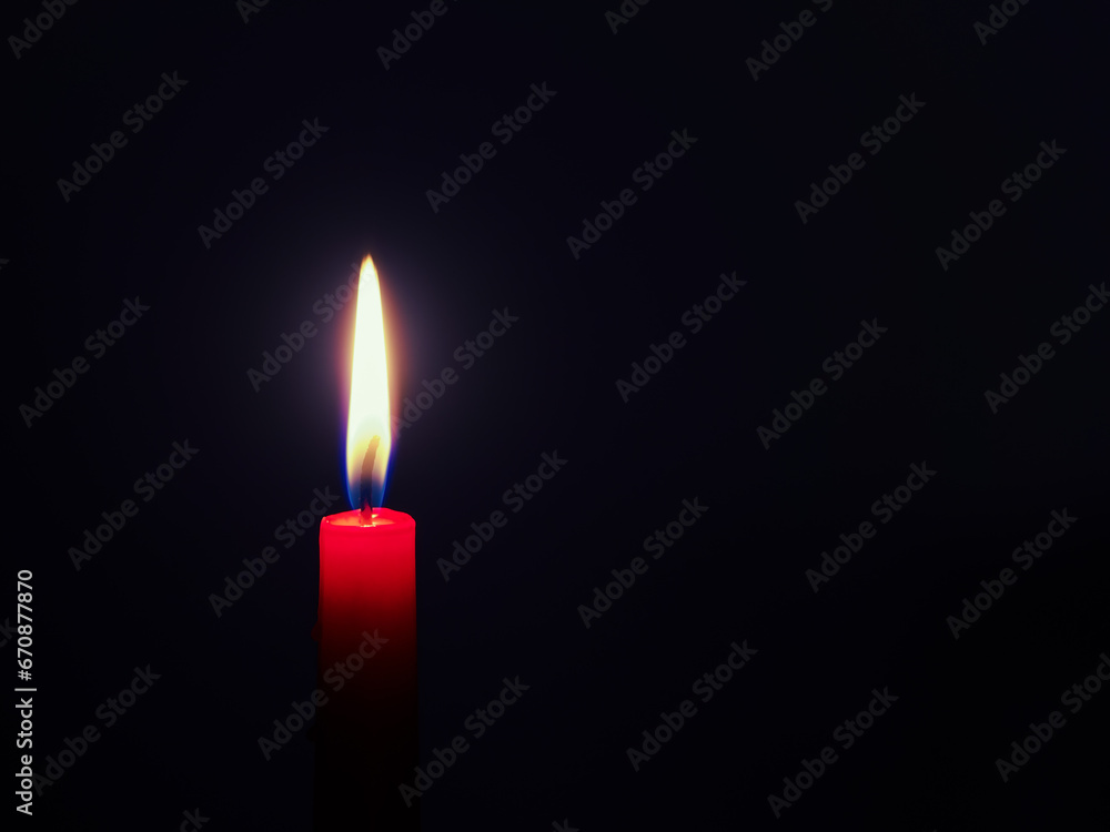 Burning red candle in front of a very dark blue background
Burning red candle in front of a very dark blue background