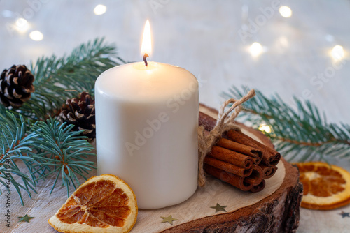 Christmas decoration with candle, spruce twig, cinnamon and dried orange
