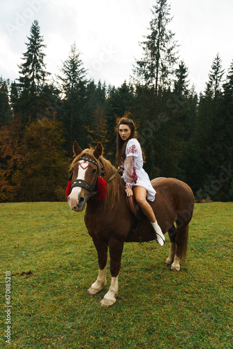 Young women ride horses in national Ukrainian dresses in the Carpathian mountains. Photo session with horses in the mountains. Ukrainian culture concept