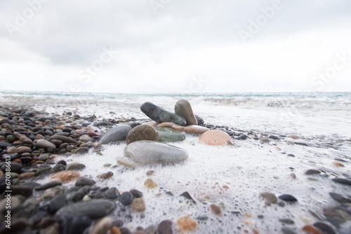 Large pebbles in sea foam against the background of the sea.