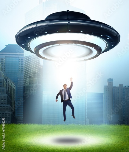 Flying saucer abducting young businessman photo