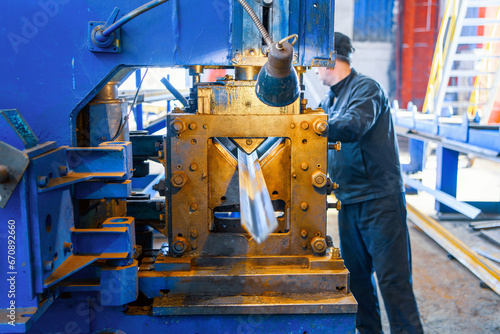 A hydraulic machine at a plant for bending sheet metal. Industrial worker out of focus working on a CNC machine in the metallurgical industry.