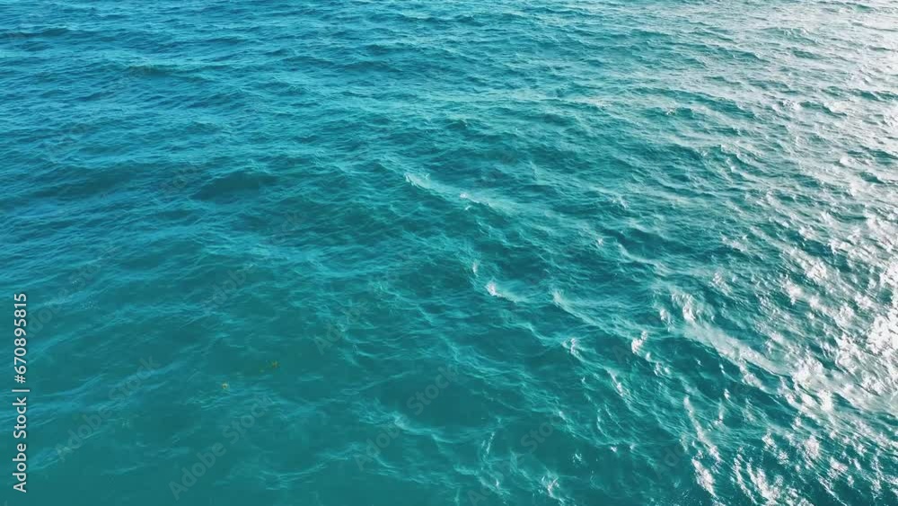 Bird's eye view of the ocean. Turquoise water ripple background texture. Waves of the Caribbean Sea on a bright sunny day. Bird's-eye. View of the sea surface with reflected sunlight. Bird's eye view of the ocean. Turquoise water ripple background texture. Waves of the Caribbean Sea on a bright sunny day. Bird's-eye. View of the sea surface with reflected sunlight.