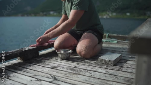 Camper Cutting Fresh Meat For Cooking On Wooden Platform By The Lakeshore. static photo