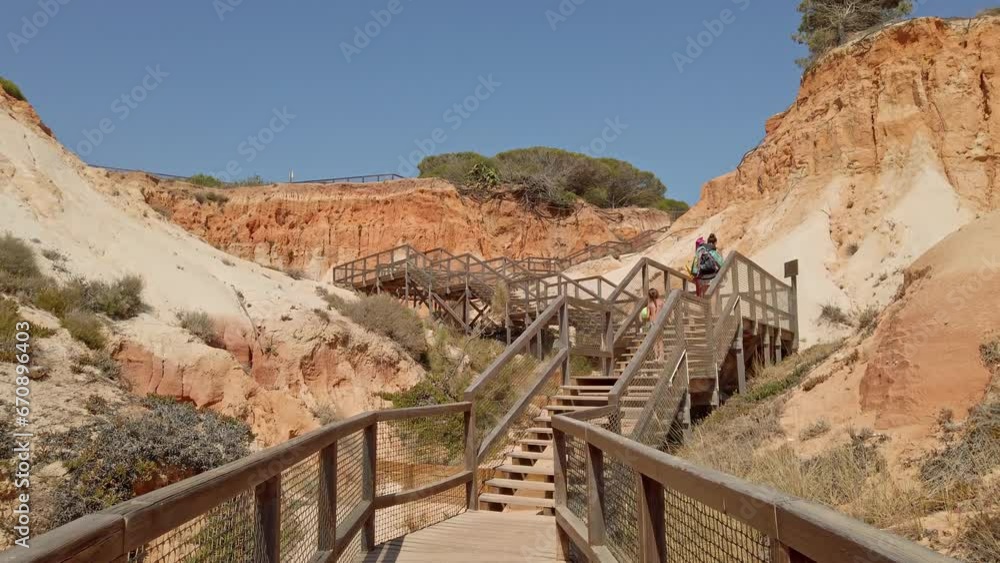 People Climbing Up The Wooden Stairs At Praia da Falesia In Algarve, Portugal. Wide Shot People Climbing Up The Wooden Stairs At Praia da Falesia In Algarve, Portugal. Wide Shot
