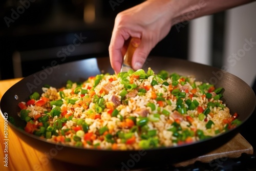 hand garnishing fried rice with fresh green onions
