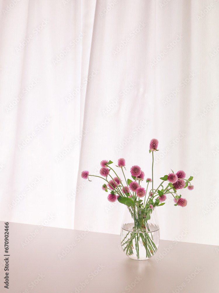 Pink Oleander Flowers in a Glass Vase, Swirling Curtain in the Background.	