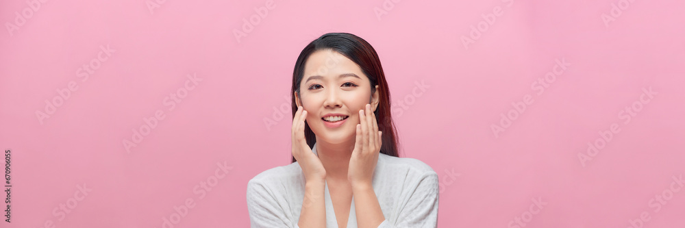 Smiling beautiful Asian woman touching her face on isolated studio pink background. Panorama Smiling beautiful Asian woman touching her face on isolated studio pink background. Panorama