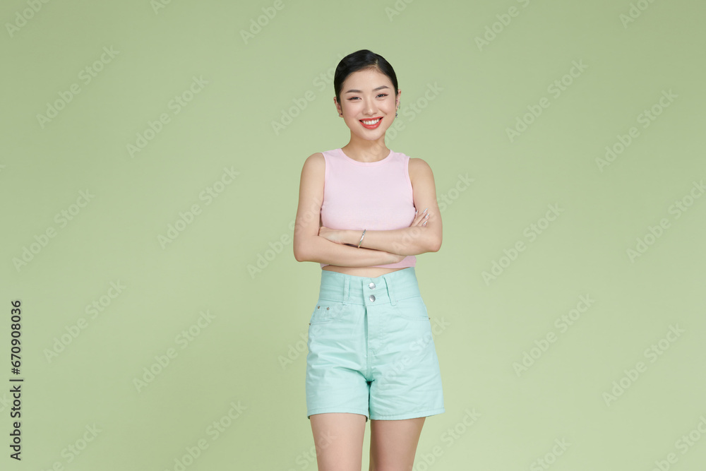 Smiling woman with arms crossed standing against pastel green background Smiling woman with arms crossed standing against pastel green background