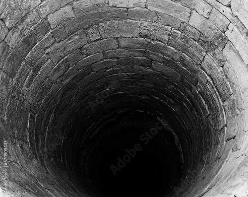 narrow tunnel or a bottomless pit made of rocks in black and white