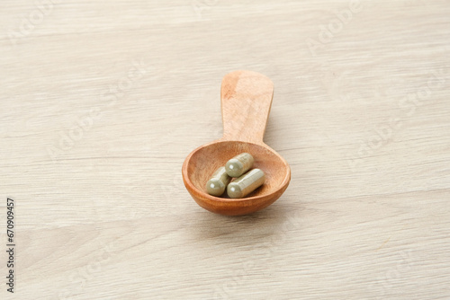 Herbal medicine in capsules in a wooden spoon
 photo