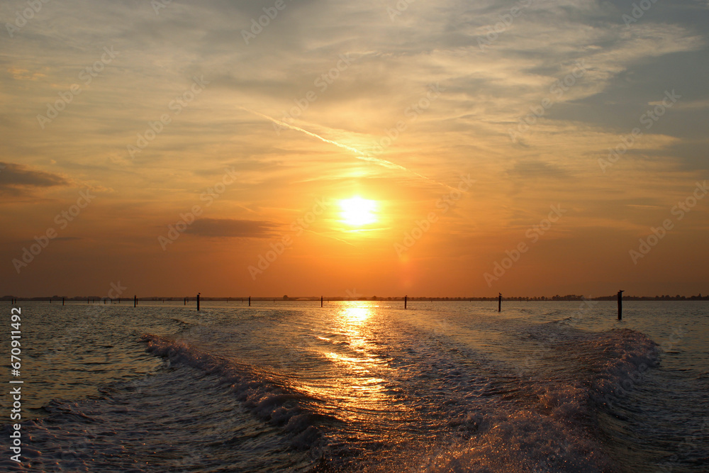 sunset over the sea with waves from boat