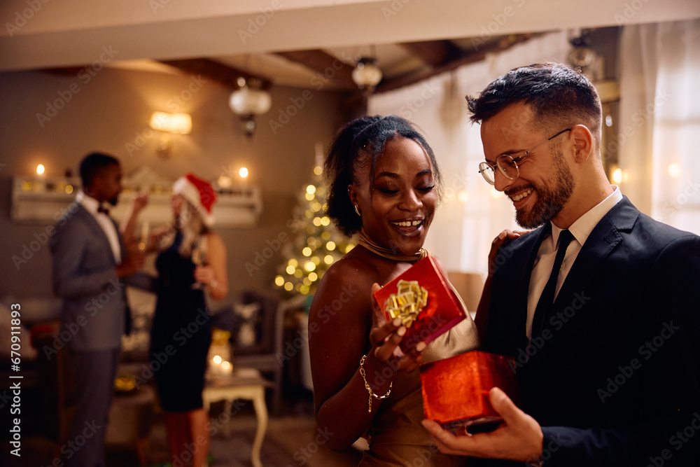 Happy black woman getting surprise gift from her boyfriend on New Year's eve.
