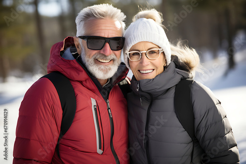 Beautiful elderly heterosexual Caucasian couple in warm jackets hugging  smiling and looking at camera