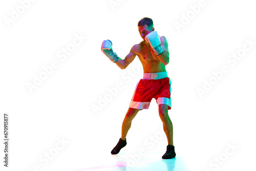 Energetic young man, sportsman, boxer, fighter exercising before fight against white background in mixed neon filter, light.