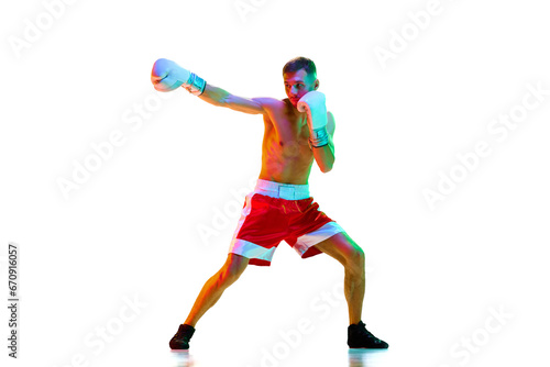 Emotional man, sportsman, boxer, fighter exercising before fight against white background in mixed neon filter, light.