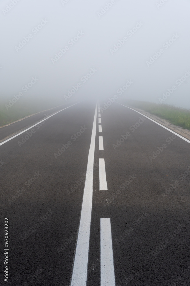 Asphalt road in the heavy fog with clear road markings, Pieniny mountains, Poland