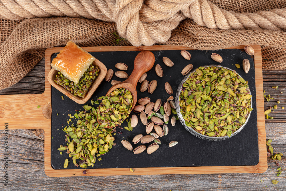 Chopped cut pistachio nuts Concept. Pistachios prepared for presentation in a copper bowl and on black marble. Ground, Milled, Crushed or Granulated Pistachio Powder.