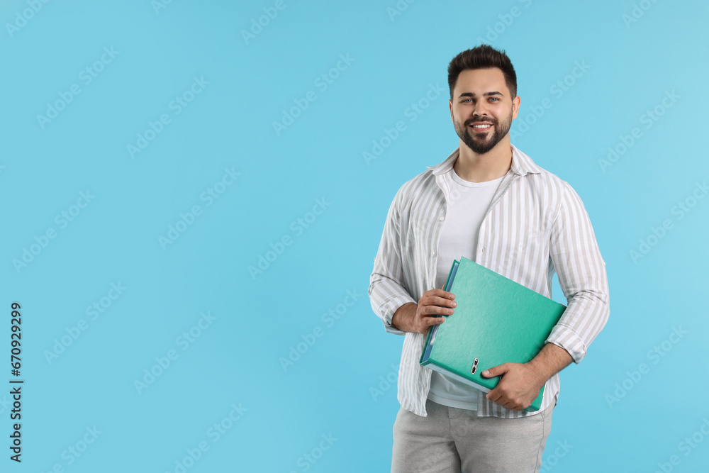 Happy man with folder on light blue background, space for text