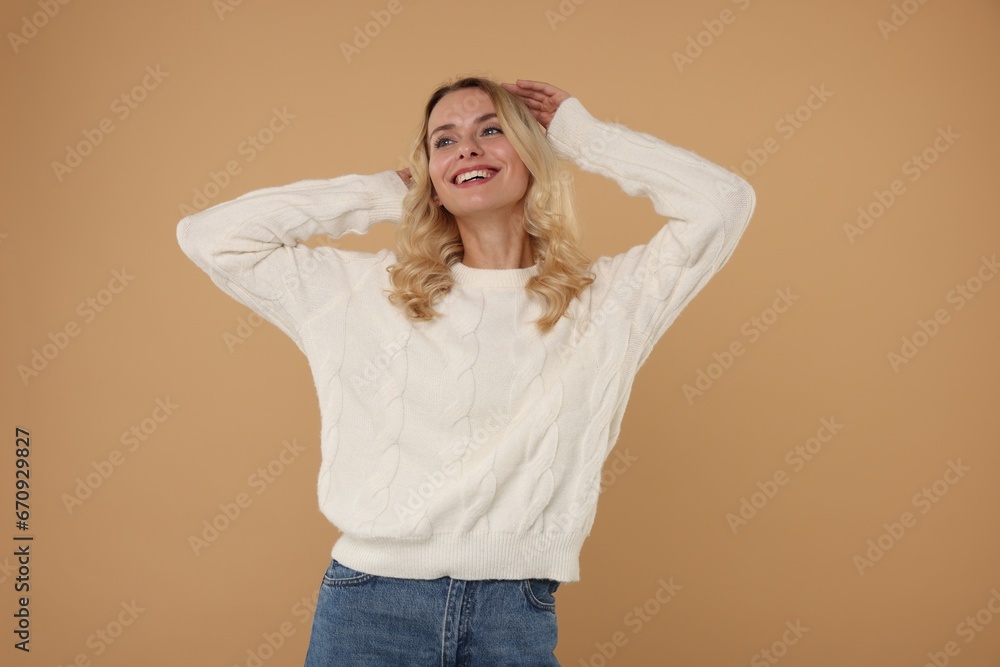 Happy woman in stylish warm sweater on beige background Happy woman in stylish warm sweater on beige background
