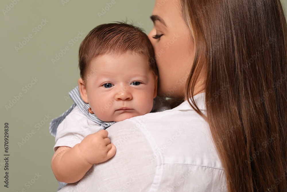 Mother kissing her cute newborn baby on olive background Mother kissing her cute newborn baby on olive background
