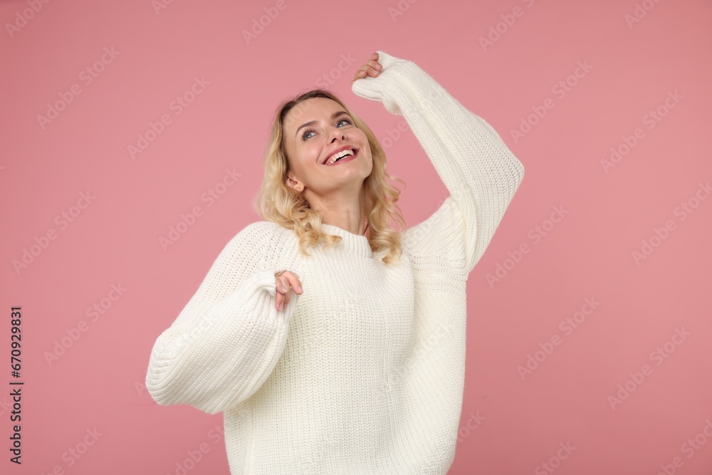 Happy woman in stylish warm sweater on pink background Happy woman in stylish warm sweater on pink background