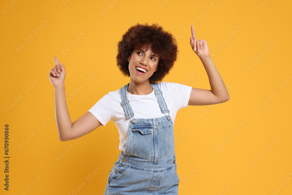 Happy young woman dancing on orange background Happy young woman dancing on orange background