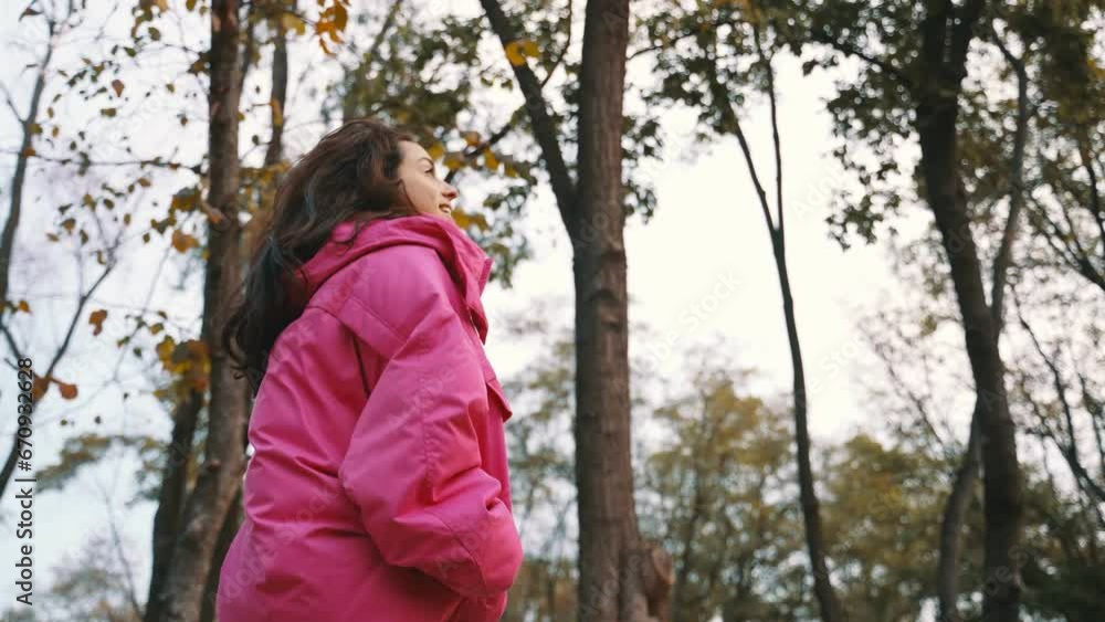 Smiling stylish lady in pink jacket walking in the autumn park and enjoying the view. Autumn urban street fashion style. Fall season. Real time Smiling stylish lady in pink jacket walking in the autumn park and enjoying the view. Autumn urban street fashion style. Fall season. Real time