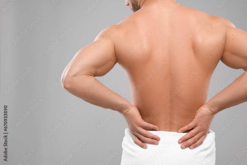 Naklejka premium Man suffering from back pain on grey background, closeup. Space for text