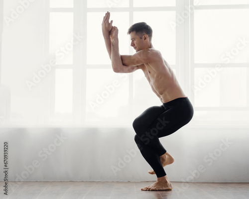 Strong male athlete standing in yoga position and stretching, Yoga stretch: male athlete showcases strength in pose.