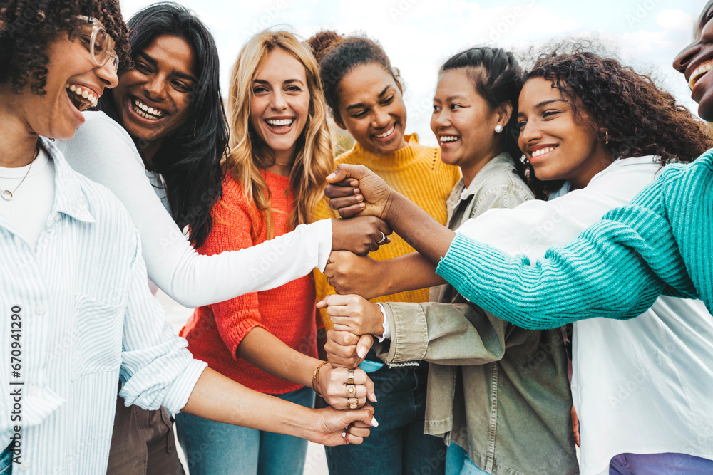 Multicultural group of women stacking hands together - Female community concept with different girls support each other - Girlfriends hugging outdoors - obrazy, fototapety, plakaty 