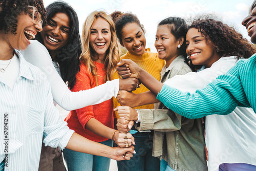 Multicultural group of women stacking hands together - Female community concept with different girls support each other - Girlfriends hugging outdoors