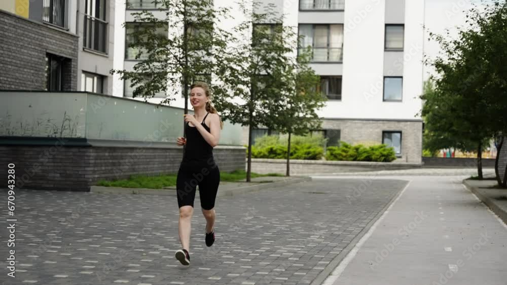 A girl jogging against the background of a residential area. Slow motion, girl in black clothes jogging A girl jogging against the background of a residential area. Slow motion, girl in black clothes jogging