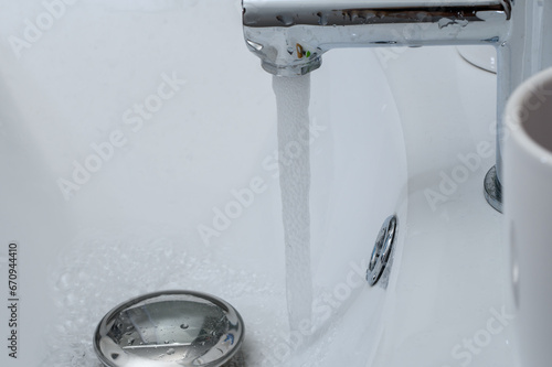 Odkręcony kran w umywalce w łazience, oszczędzać wodę 