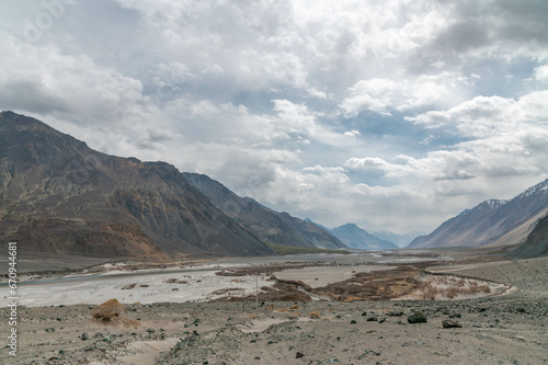 Valley between mountains on a cloudy day. A Dried river trains of Shyok river in Nubra Valley in Ladakh Region of Indian Himalayan territory .A Barren landscape of Cold dessert in Himalaya Valley .